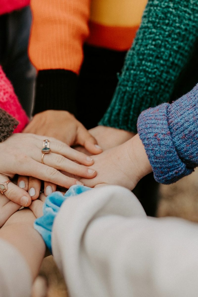 person in red sweater holding babys hand